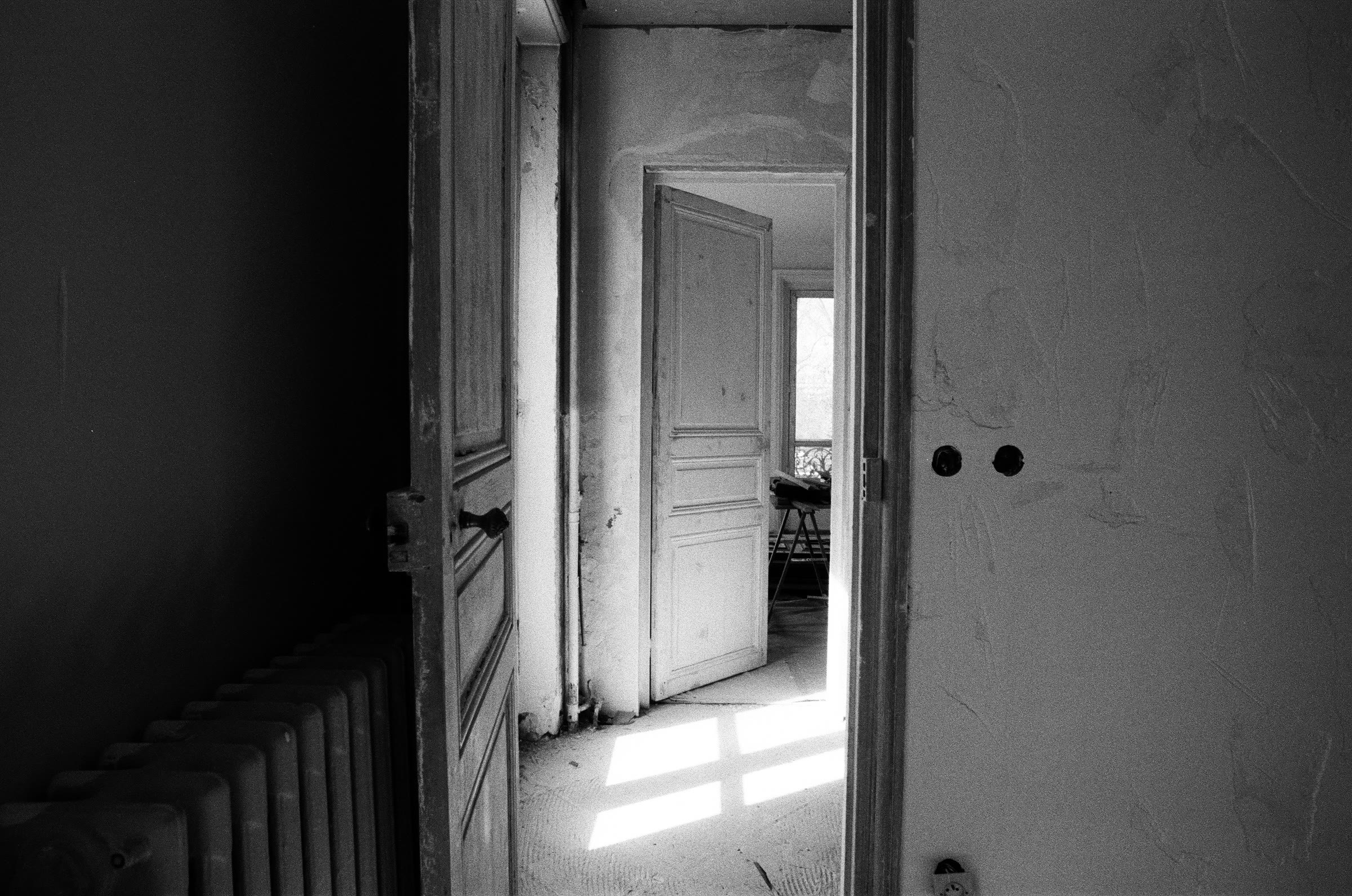 Chantier, couloir sombre, porte et radiateur d’origine